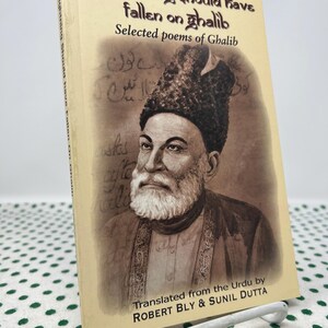 May include: A book titled "The Lightning Should Have Fallen on Ghalib" with a portrait of Ghalib on the cover. The book is a collection of selected poems by Ghalib, translated from the Urdu by Robert Bly and Sunil Dutta.