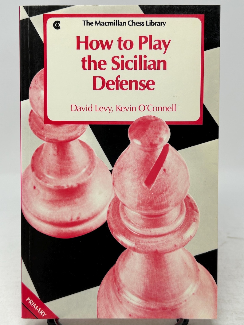 K&ouml;nnte beinhalten: Buchcover "How to Play the Sicilian Defense" aus der The Macmillan Chess Library. Es zeigt ein rot-wei&szlig;es Schachfigurendesign auf einem schwarz-wei&szlig; karierten Hintergrund. Autoren sind David Levy und Kevin O'Connell.