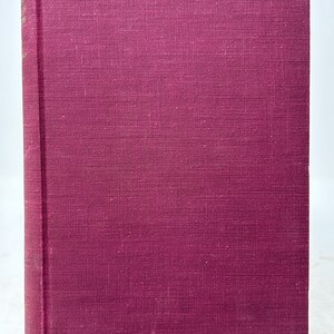 May include: A hardcover book with a deep burgundy cover. The cover has a textured appearance, and the spine shows faded text. The book is standing upright, suggesting it is ready to be read or displayed.