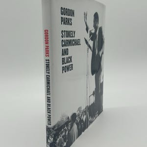 May include: A hardcover book titled "Gordon Parks, Stokely Carmichael and Black Power." The cover features a black and white photograph of a man speaking at a podium with a crowd in the background. The book's spine also displays the title.