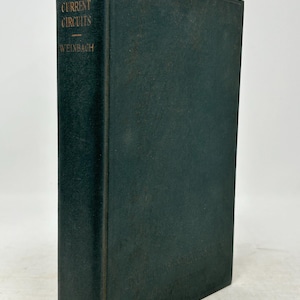 May include: A vintage hardcover book titled "Alternating Current Circuits" by Weinbach. The book has a dark green cover with gold lettering. The Macmillan publishing logo is visible at the bottom of the spine.