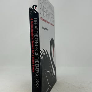 May include: A book titled "LIFE AT THE CENTER OF THE ENERGY CRISIS" by George R. Miley. The cover features a black swan illustration with red accents. The spine displays the author's name and the book's title, with the publisher's logo at the bottom.
