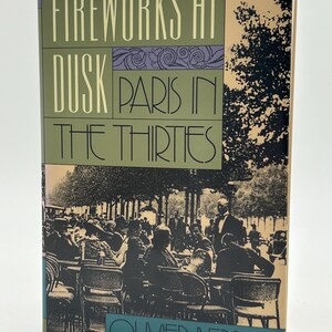 Może przedstawiać: Książka w twardej oprawie zatytułowana "Fireworks at Dusk Paris in the Thirties" autorstwa Oliviera Berniera. Okładka przedstawia ilustrację w stylu vintage sceny z paryskiej kawiarni w czerni i bieli, z tekstem w kolorze zielonym, fioletowym i turkusowym.