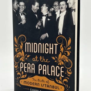 May include: A hardback book titled "Midnight at the Pera Palace" by Charles King. The cover is black with gold lettering and decorative flourishes. A black and white photo of men in tuxedos is at the top of the cover.
