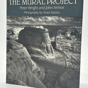 May include: A book titled "THE MURAL PROJECT" with photography by Ansel Adams. The cover features a black and white landscape photograph of a canyon and river. The title and author's names are in white text.