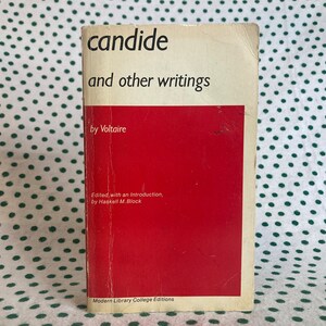 May include: A red paperback book with the title "candide and other writings" by Voltaire. The book is part of the Modern Library College Editions series.