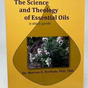 May include: A book with a yellow cover, titled "The Science and Theology of Essential Oils". It has a photo of white and pink flowers within a brown diamond shape. The author's name, Dr. Marcus O. Durham, is printed at the bottom.