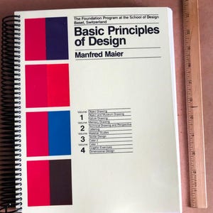 Puede incluir: Un libro blanco con un esquema de color rojo, azul y negro. El título es "Principios básicos del diseño" de Manfred Maier. El libro forma parte de una serie, con los volúmenes 1 a 4 listados en la portada.