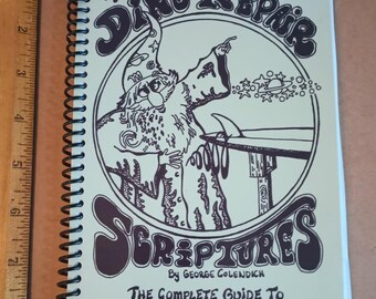 Op de afbeelding: Een vintage boek getiteld "The Ding Repair Scriptures" van George Colendich. De omslag toont een cartoonillustratie van een tovenaar met een surfboard en sterren. Het boek is een complete gids voor het repareren van surfplanken.