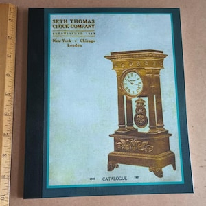 Peut inclure: Une couverture de catalogue vintage de la Seth Thomas Clock Company représentant une horloge dorée avec un cadran romain et un pendule. La couverture est vert sarcelle avec des bordures noires et le texte "Seth Thomas Clock Company Established 1813 New York Chicago London 1906 Catalogue 1907".