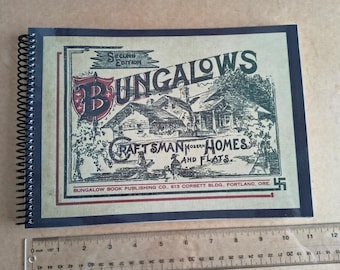 Puede incluir: Un libro encuadernado en espiral titulado "Bungalows, Craftsman Modern Homes and Flats". La portada presenta una ilustración de una casa y texto en un estilo vintage. El libro está sobre una superficie marrón claro con una regla.