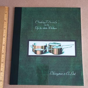 May include: A green book with a black spine titled "Cooking Utensils for the Up-to-date Kitchen" by Elkington & Co Ltd. The cover features a drawing of copper pots and pans.