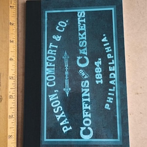 May include: A black book with a blue and white label that reads "Paxson, Comfort & Co. Coffins and Caskets 1884. Philadelphia."