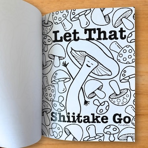 Puede incluir: Una p&aacute;gina de libro para colorear en blanco y negro con ilustraciones de hongos. El texto "Let That Shiitake Go" se muestra en negrita, con una fuente estilizada. La p&aacute;gina est&aacute; abierta, revelando una p&aacute;gina en blanco a la izquierda.