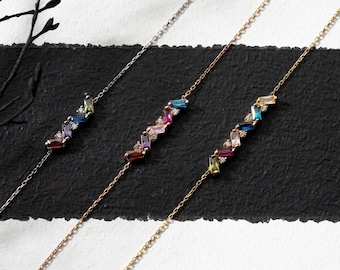 May include: Three delicate gold, silver, and rose gold chains with colorful gemstone accents. Each chain features a row of baguette-shaped gemstones in a rainbow of colors.