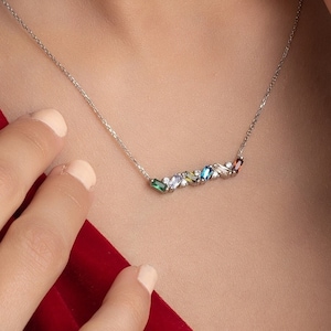 May include: A silver necklace with a delicate chain and a row of colorful gemstones. The gemstones are arranged in a line and are of various shapes and sizes.