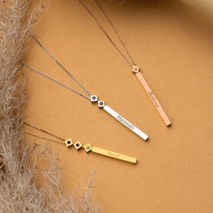 May include: Three gold necklaces with personalised name bars. The necklaces feature small cubic zirconia stones. The names on the bars are "David", "Hannah", and "Melissa".