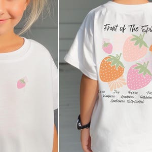 May include: White t-shirt with a strawberry graphic on the front and the text "Fruit of The Spirit" with a strawberry graphic and the text "Love, Joy, Peace, Patience, Kindness, Goodness, Faithfulness, Gentleness, Self-Control" on the back.