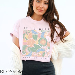 May include: Pink t-shirt with a floral design and the text "It is well with my soul".