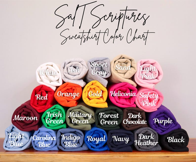 May include: A color chart showing the different sweatshirt colors available. The colors include white, ash, sport gray, sand, light pink, red, orange, gold, heliconia, safety pink, maroon, irish green, military green, forest green, dark chocolate, purple, light blue, carolina blue, indigo blue, royal blue, navy, dark heather, and black.