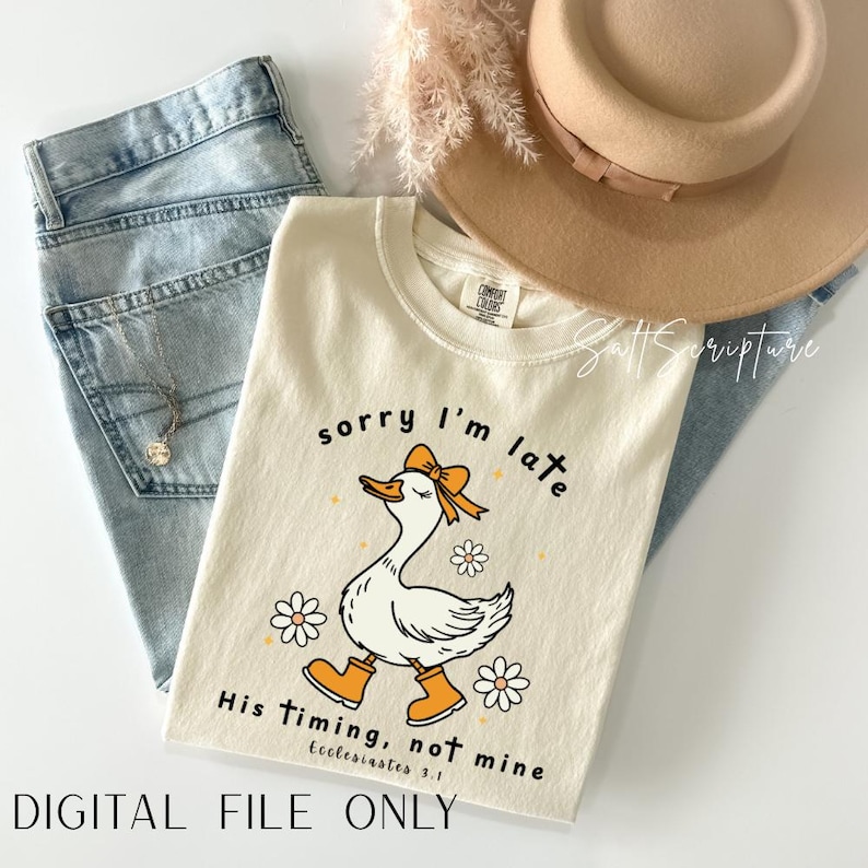 May include: Cream-colored t-shirt with a cartoon goose wearing a bow and boots, the text "sorry I'm late" and "His timing, not mine" with Ecclesiastes 3:1. The shirt is paired with light blue jeans and a tan hat. The words "DIGITAL FILE ONLY" are at the bottom.