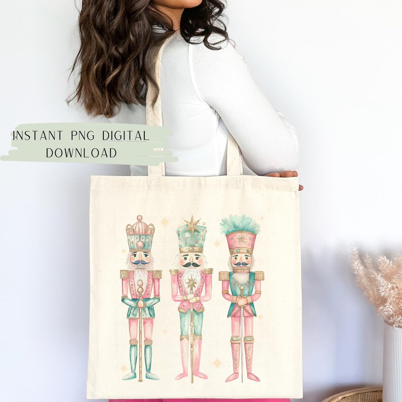 May include: A white tote bag with a design of three watercolor nutcracker soldiers. The nutcrackers are wearing pink, green, and blue uniforms with gold accents. The bag has the text "INSTANT PNG DIGITAL DOWNLOAD" at the top.