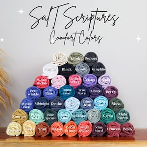 May include: A display of rolled up fabric swatches in various colours, including black, white, blue, green, red, orange, yellow, and purple. The fabric swatches are arranged in a pyramid shape. The text "Salt Scriptures Comfort Colors" is at the top of the image.