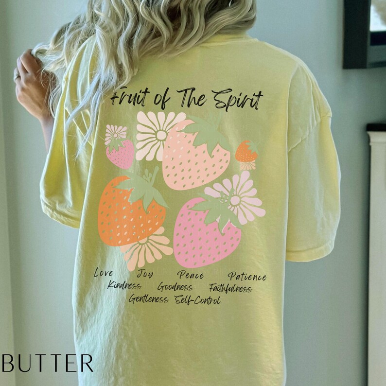 May include: A yellow t-shirt with the text "Fruit of the Spirit" and a graphic of strawberries and flowers. The text "Love, Joy, Peace, Patience, Kindness, Goodness, Faithfulness, Gentleness, Self-Control" is printed below the graphic.