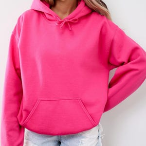 May include: A vibrant pink hoodie with a drawstring hood and a kangaroo pocket. The sweatshirt is a solid color and appears to be made of a soft material. The hoodie is a casual garment.