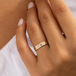 May include: A gold ring with the inscription "with all my heart" engraved on the band. The ring is worn on a finger, and the image is set against a white background.