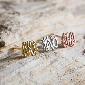 May include: Three gold, silver, and rose gold monogram earrings with a delicate script font.
