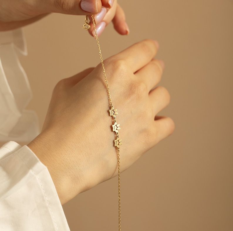 May include: A gold chain bracelet with a series of small paw print charms.