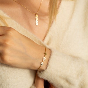 May include: A gold necklace and bracelet with a paw print design. The necklace has a long pendant with multiple paw prints. The bracelet has a shorter chain with several paw prints.
