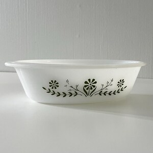 May include: White oval baking dish with a green floral design. The design features small flowers and leaves.