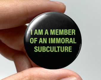 May include: Black button with the text "I AM A MEMBER OF AN IMMORAL SUBCULTURE" in green letters.