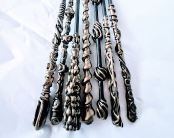 May include: A set of ten black and gold wands with intricate designs. The wands are arranged in a fan shape on a white surface.