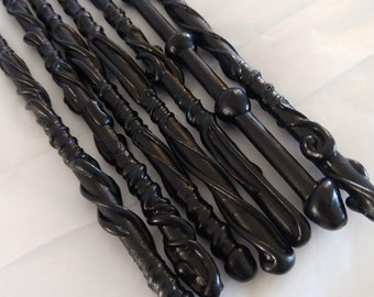 May include: A set of eight black wooden wands with intricate designs and different tip styles. The wands are arranged in a row, with the tips pointing in different directions.