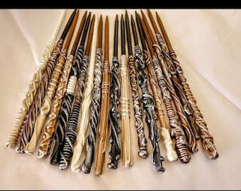 May include: A collection of 18 intricately carved wooden wands, each with a unique design and finish. The wands are painted in various shades of brown, black, and white, with some featuring metallic accents.