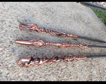 May include: Three black and copper wands with intricate details. The wands are made of a dark material with a copper-colored finish. The wands are all different lengths and have unique designs.