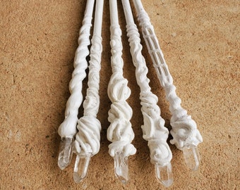 May include: Four white wands with crystal tips. The wands are made of a white material and have a swirling design. The wands are arranged in a fan shape.