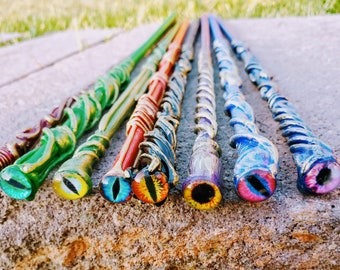 May include: A set of ten colorful wands with a unique eye design at the end of each wand. The wands are painted in various colors, including green, blue, red, and yellow.