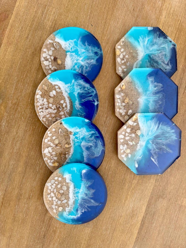 May include: Set of six resin coasters featuring a beach scene with blue, white, and brown colors. The coasters are round and octagonal.