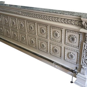 May include: A white wooden bar counter with a granite top and intricate carved details. The front of the counter features a repeating pattern of raised floral designs within square frames.