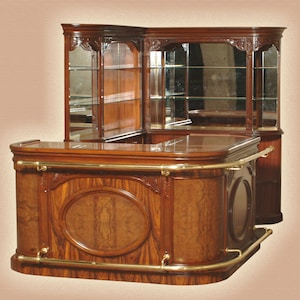 May include: A dark wood corner bar unit with a glass-front cabinet and a built-in bar counter. The bar counter has a brass rail and a decorative carved design.