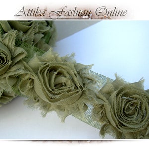 May include: Green fabric flower trim with a ruffled texture. The trim is made of multiple layers of fabric and has a delicate, feminine look.