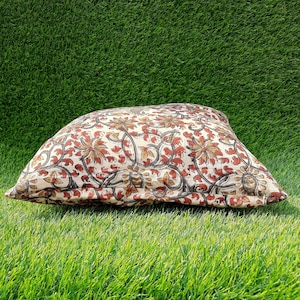 May include: A cream-colored pillow with a floral pattern in shades of brown, red, and beige. The pillow is made of cotton and has a soft, comfortable feel.
