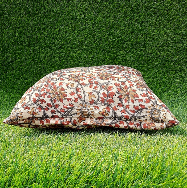 May include: A cream-colored pillow with a floral pattern in shades of brown, red, and beige. The pillow is made of cotton and has a soft, comfortable feel.