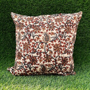 May include: A cream-colored pillow cover with a floral pattern in shades of brown and red. The pillow cover features a repeating design of stylized flowers and leaves.