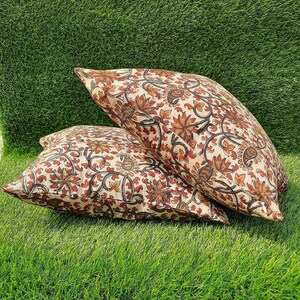 May include: Two cream-colored pillow covers with a floral pattern in shades of brown and red. The floral pattern features intricate designs of leaves and flowers.