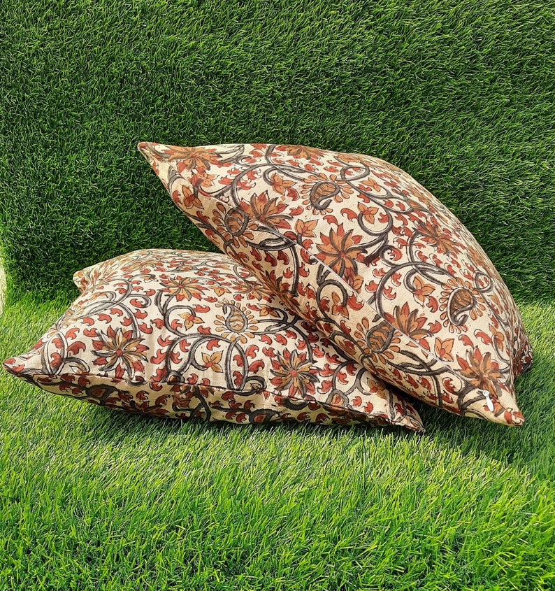 May include: Two cream-colored pillow covers with a floral pattern in shades of brown and red. The floral pattern features intricate designs of leaves and flowers.